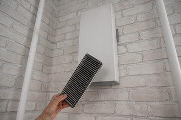 A man changes the filter at the supply ventilation. Gadget for ventilation, disinfection and air...