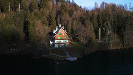 Aerial pullback parallax establishes beautiful wooden lakehouse nestled in forest