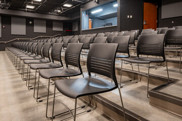 Photo of a new school theater, auditorium, with gray seats, chairs.	