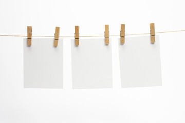 Empty paper frames that hang on a rope with clothespins and isolated on white. Blank cards on rope. Mockup template for memories backdrop, photos, social media etc.