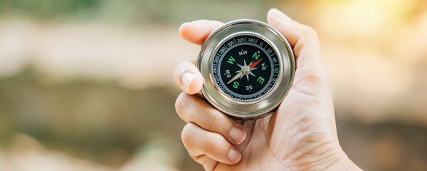 Traveler grasps a compass in park using it to overcome confusion. compass in her hand symbolizes...