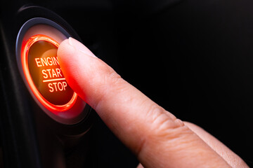 The driver's hand is pressing the car start button. Concept of transportation and technology	