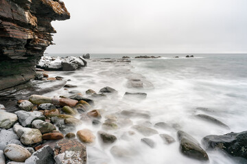 Rocky shores of the Varangerfjord on a cloudy and gray day during the polar night, Ekkerøya, Northern Norway