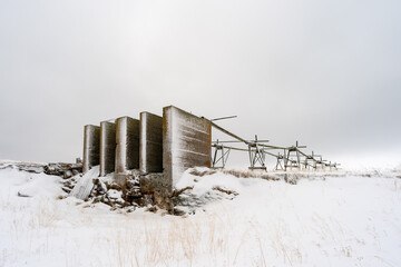 War time concrete structure and fish drying racks on a cloudy winter day during the polar night,...