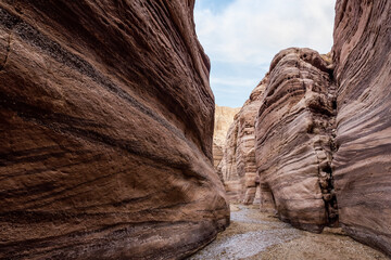 A shallow  stream flows between rocks painted with intricate natural patterns at beginning of the Wadi Numeira walking trail in Jordan