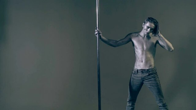 Strip dancer. Fit slim muscular man on pole dance. Pole dancer on pylon. Shirtless strong sexy man dancing. Male flexibility, and grace. Guy performing trick on pole. Male athlete doing acrobatic