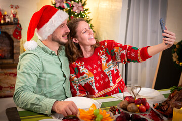 Young couple taking a selfie at a Christmas party at home