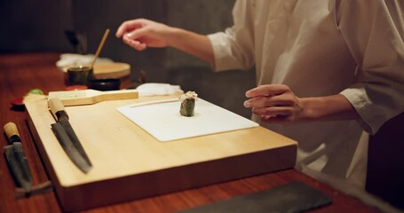 Sushi, fish and closeup of chef hands cooking on table at diner, cuisine or restaurant at night. Kitchen, career and zoom of culinary artist preparing a gourmet Japanese meal or snack at catering job