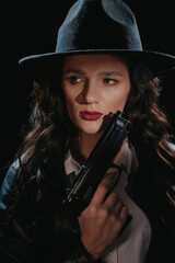 Close-up portrait of a female detective in a coat and hat with a gun in her hands. A book drama...