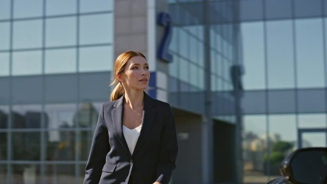 Happy woman unlocking car using distance key at business district. Rich lady