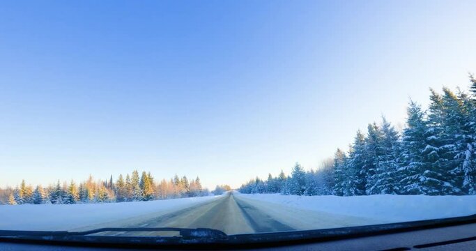 Snowy Forest Road Adventure: Front View Drive in Winter. Embark on a winter adventure with this compelling POV shot of a car driving through a beautiful forest road. Revel in the front-facing view