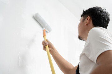 painter man, brush in hand for products to restore and paint the wall, indoor the building site of...