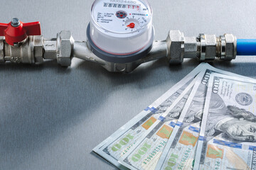 Water meter, water pipe with dollar banknotes on dark surface.  Concept of water consumption, price and costs concept.