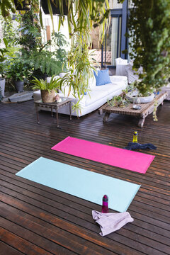 Modern big empty house with yoga mats on terrace with couch in big green garden