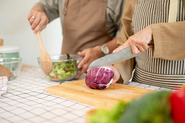 A wife chopping vegetables, cooking, and making a healthy breakfast with her husband in the kitchen.