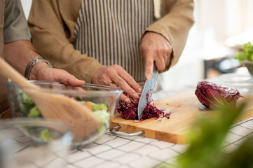 A wife chopping vegetables, cooking, and making a healthy breakfast with her husband in the kitchen.