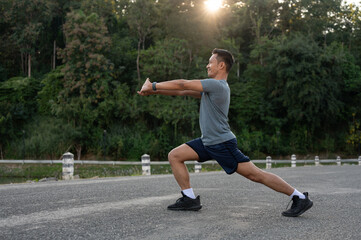 A strong, athlete Asian man in sportswear is stretching his body, warming up before exercise or...