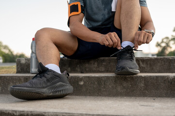 Obraz premium A man in sportswear sitting on the stairs and tying his shoelaces, getting ready to exercise.