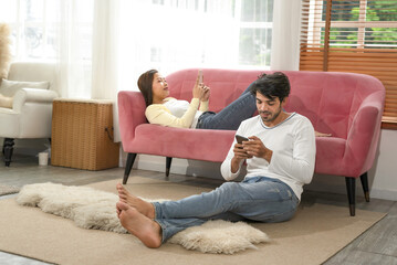 husband and wife spend their free time on weekend by using mobile phones in living room,young...