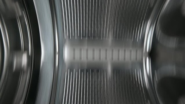 Inside view of the washing machine drum, close-up of the stainless steel drum during the spin cycle. Metallic pattern.
