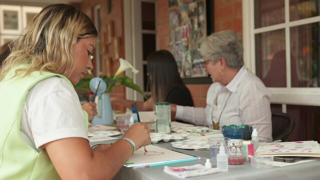Group of Hispanic women painting with  watercolors in workshop