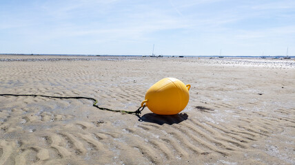 Yellow buoy on the sand beach on the shoreline in low tide