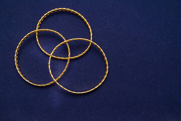 24k (24 carat) Turkish gold twist bracelet standing in a heap on a dark blue background in the gold...