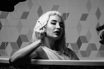 Portrait of a young beautiful blonde girl in a vintage style bathroom. Black and white photo.