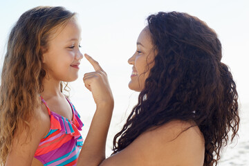 Happy mother, girl and poking nose at beach for love, care or support for child or daughter in...