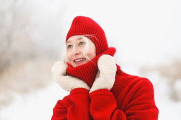 A girl in a red sweater and a red hat is enjoying the winter weather. Bright winter. Winter fashion.