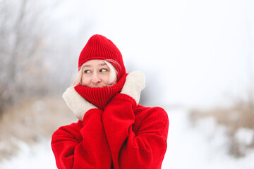 Obraz premium A girl in a red sweater and a red hat is enjoying the winter weather. Bright winter. Winter fashion.