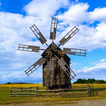 Photo of a windmill, taken in a picturesque rural landscape. A stationary windmill in windless weather. Square image.