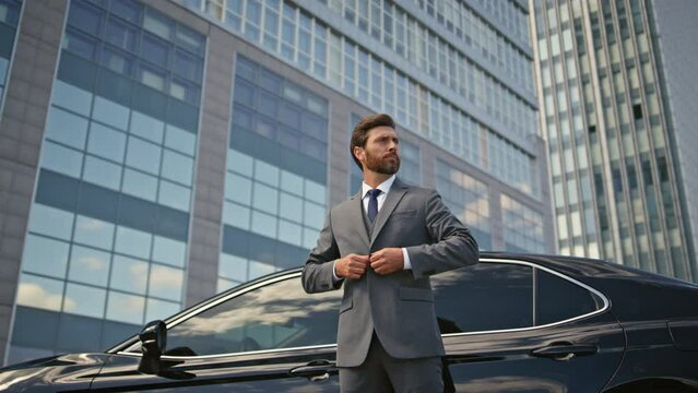 Rich businessman posing car buttoning jacket. Elegant man standing urban street