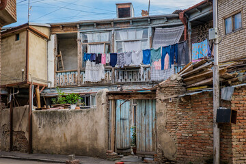 Fototapeta na wymiar Old crumbling traditional georgian house with wooden balcony and laundry drying on a clothesline in Kala, Tbilisi old town (Georgia)