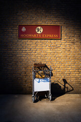 Naklejka premium JAPAN - NOV 13, 2023: Hogwarts Express platform 9¾ with owl bird cage and boxes in the shopping cart go to the wall, at Warner Bros. Studio Tour Tokyo, The Making of Harry Potter, Wizarding World