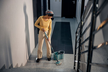 A japanese cleaner is cleaning stairs in building hall.