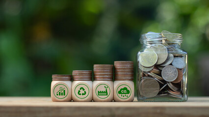 Carbon credit concept. Wooden cubes with CO2 icon on stack of silver coins and glass coin jar. Tax...
