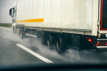 View from a car of a truck driving on highway on rainy weather.