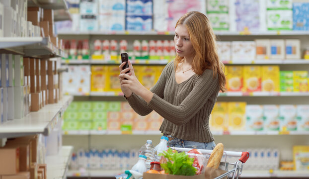 Woman checking products at the supermarket using a food scanner app