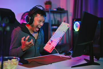 Angry gamer screaming and breaks keyboard, upset because of losing the game.
