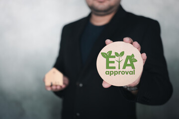 Businessmen holding tag of approval EIA or environmental impact assessment, taking into account the...