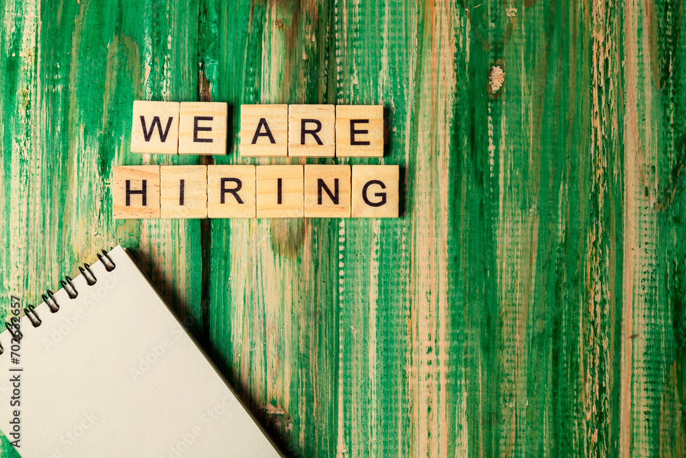 Poster wooden cubes with we are hiring letters and an empty notebook