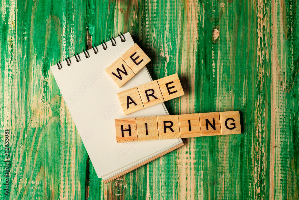 Poster wooden cubes with we are hiring letters and an empty notebook
