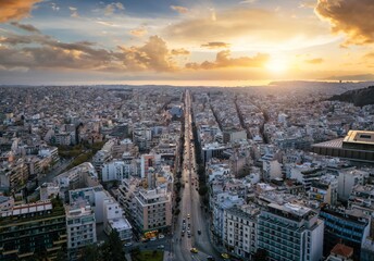 Aerial view of the skyline of Athens, Greece, with Syggrou Avenue leading straight down to the sea during sunset time