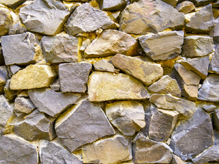 Close-up image of the wall. Rough, natural stone texture. Stone of different sizes and shapes. Template for interior design, websites or promotional materials. Horizontal image.