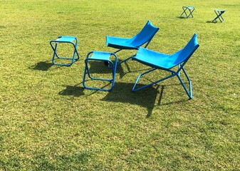 Two blue sun loungers on the lawn and small folding chairs for relaxing in the summer sun.