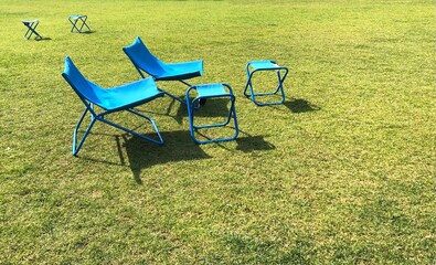 Two blue sun loungers on the lawn and small folding chairs for relaxing in the summer sun.
