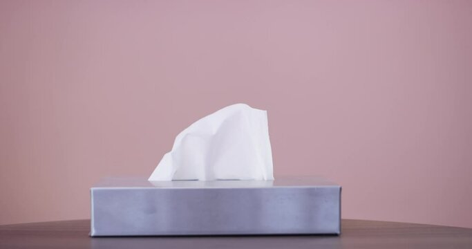 Tissue, box and hands of person in a studio with soft toiletry product for health recovery. Closeup, hygiene wipe and closeup of model with paper napkin in container isolated by pink background.