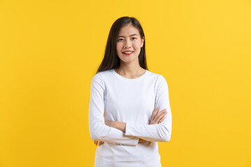 Cute asian young woman in white shirt casual look posing confidence folded arms isolated on yellow...