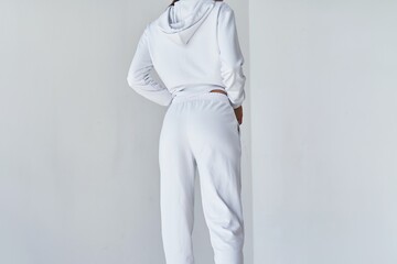 Back view of a young woman wearing white minimalist sweatpants. Step into Comfort with a Chic White Outfit Perfect for Casual Elegance. Sportwear mock-up. Girl in white pants.